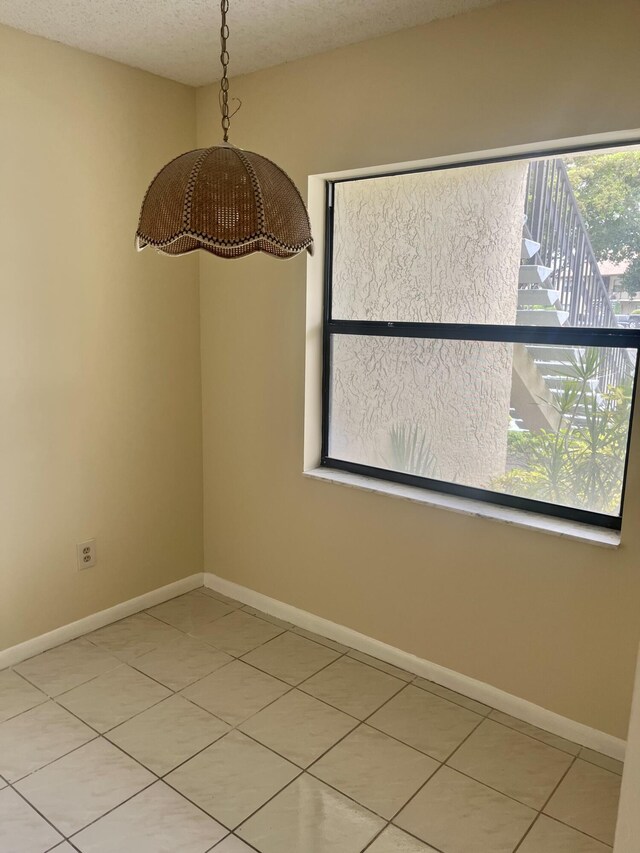 3529 Englewood Dr Unit 313, Lake Worth, FL 33467 - unfurnished dining area with light tile patterned floors, baseboards, and a textured ceiling