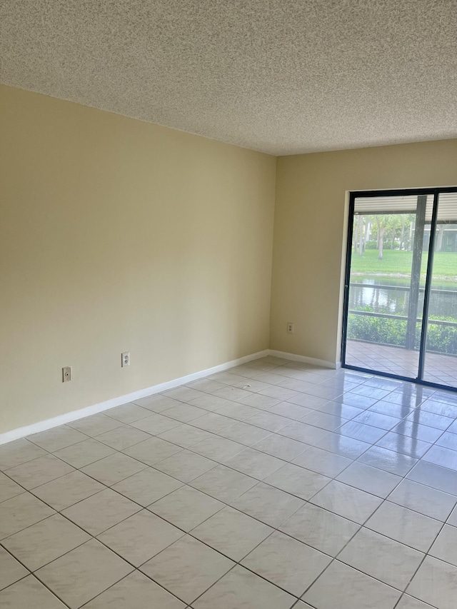 3529 Englewood Dr Unit 313, Lake Worth, FL 33467 - spare room with baseboards, a textured ceiling, light tile patterned floors, and a water view
