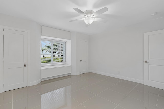 unfurnished room with baseboards, light tile patterned floors, and a ceiling fan