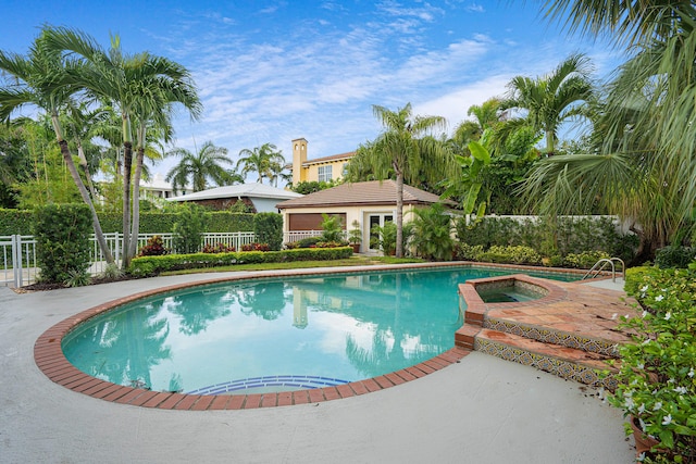outdoor pool with a patio area, an in ground hot tub, and fence