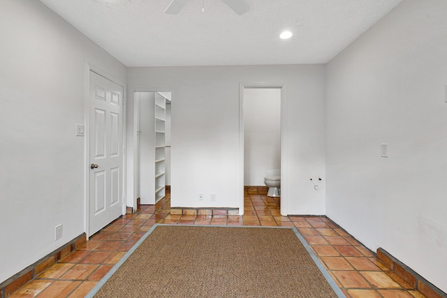 unfurnished bedroom featuring ceiling fan, ensuite bathroom, baseboards, recessed lighting, and a walk in closet