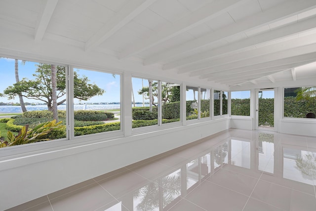 unfurnished sunroom featuring tile patterned floors, beam ceiling, and a water view