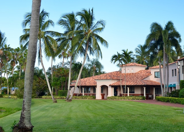 mediterranean / spanish-style house with stucco siding, a front lawn, and a tile roof