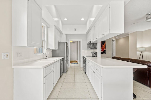 kitchen featuring a kitchen breakfast bar, light countertops, tasteful backsplash, a sink, and stainless steel appliances