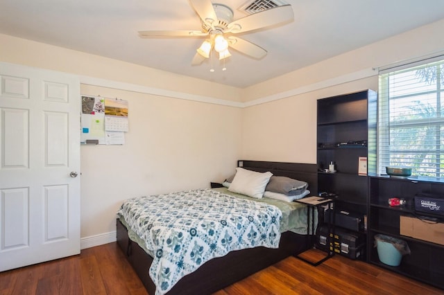 bedroom featuring baseboards, multiple windows, wood finished floors, and visible vents