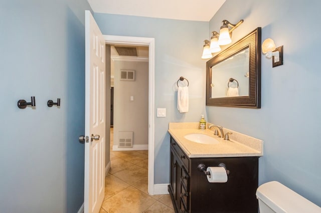 half bathroom with toilet, vanity, tile patterned floors, and visible vents