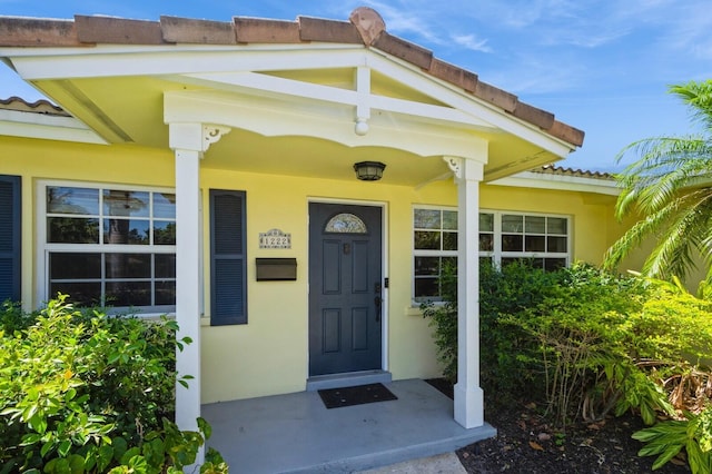 view of exterior entry featuring a tile roof and stucco siding
