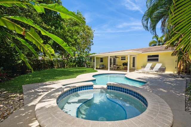 view of swimming pool with a ceiling fan, fence, a yard, a patio area, and a pool with connected hot tub