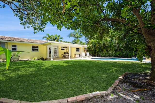 back of house with a patio area, french doors, a lawn, and stucco siding