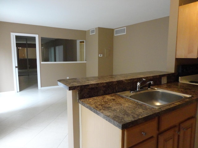 kitchen with white appliances, dark countertops, a sink, visible vents, and light tile patterned flooring
