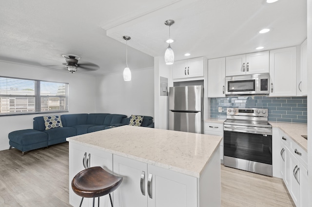 kitchen with light stone counters, appliances with stainless steel finishes, light wood-style flooring, white cabinetry, and tasteful backsplash