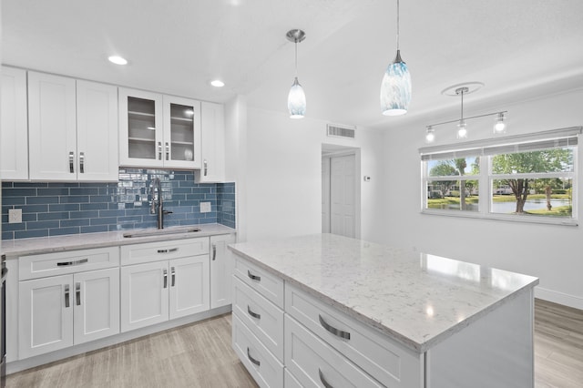 574 Monaco L, Delray Beach, FL 33446 - kitchen featuring light wood-style floors, tasteful backsplash, glass insert cabinets, light stone counters, and white cabinetry