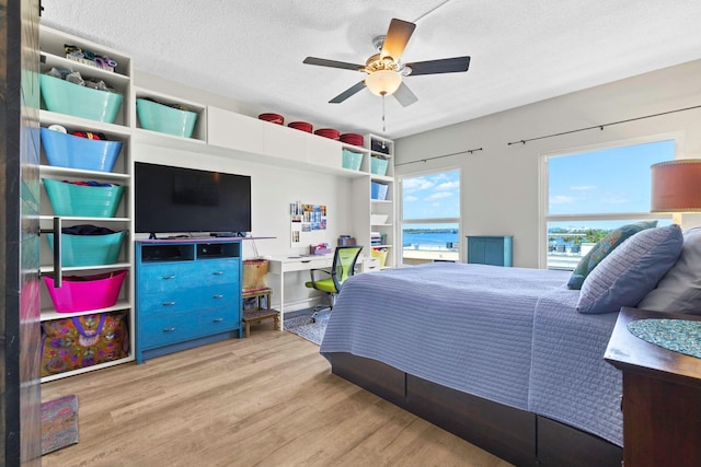 bedroom with a textured ceiling, a ceiling fan, and wood finished floors