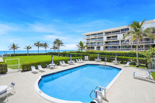 community pool featuring a patio, a water view, and fence