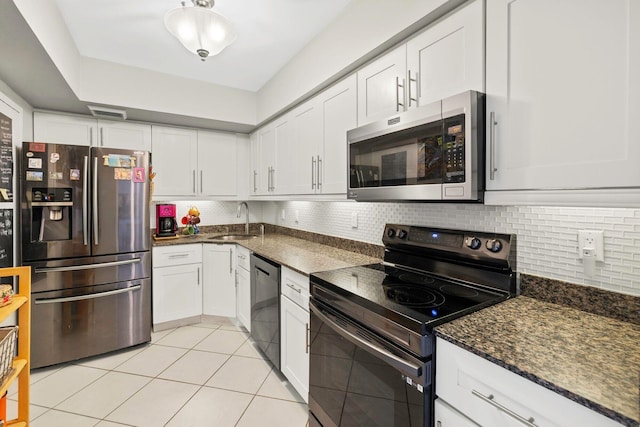kitchen featuring decorative backsplash, appliances with stainless steel finishes, white cabinets, a sink, and light tile patterned flooring