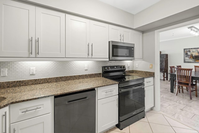 kitchen featuring appliances with stainless steel finishes, white cabinetry, tasteful backsplash, and dark stone countertops
