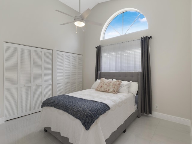 bedroom with baseboards, lofted ceiling, a ceiling fan, tile patterned flooring, and multiple closets
