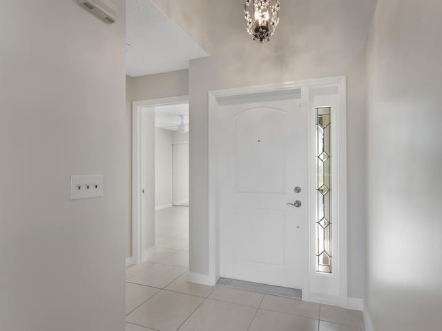 foyer with baseboards, a notable chandelier, and light tile patterned floors