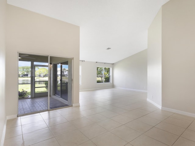empty room featuring baseboards, vaulted ceiling, and light tile patterned floors