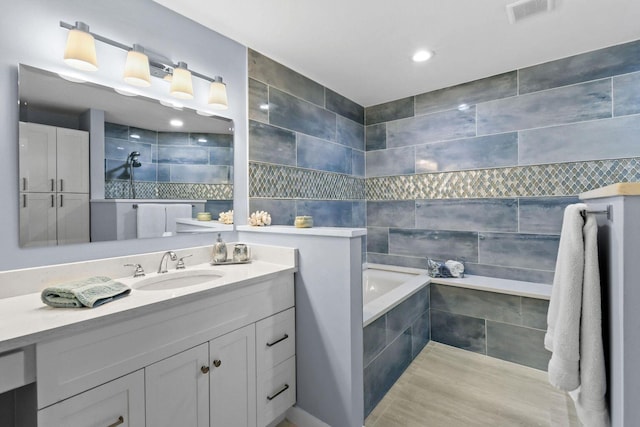 252 Legendary Cir, Palm Beach Gardens, FL 33418 - bathroom with tile walls, visible vents, recessed lighting, a garden tub, and vanity