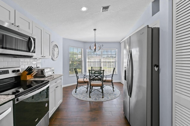 252 Legendary Cir, Palm Beach Gardens, FL 33418 - kitchen with white cabinets, stainless steel appliances, visible vents, baseboards, and a textured ceiling