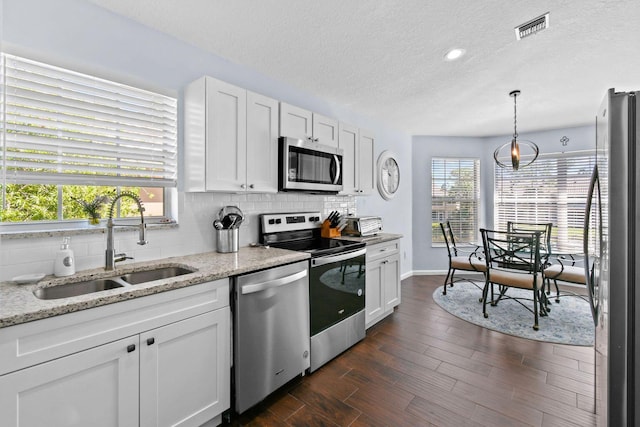 252 Legendary Cir, Palm Beach Gardens, FL 33418 - kitchen with visible vents, a sink, decorative backsplash, appliances with stainless steel finishes, and white cabinetry