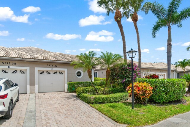 5375 Monterey Cir Unit C, Delray Beach, FL 33484 - view of front of home with a tile roof, driveway, stucco siding, and an attached garage