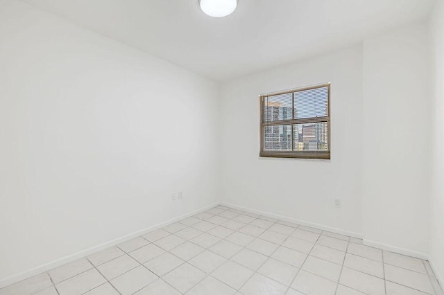 spare room with baseboards and light tile patterned floors