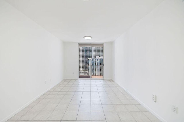 spare room featuring baseboards and light tile patterned flooring