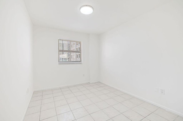 unfurnished room featuring baseboards and light tile patterned flooring