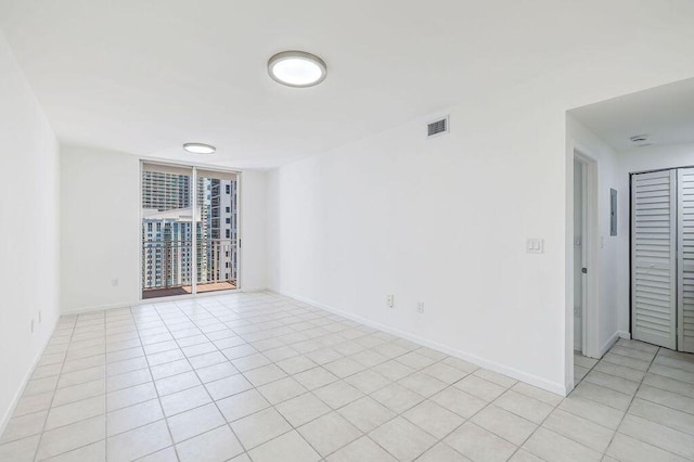 empty room featuring baseboards, visible vents, and light tile patterned floors