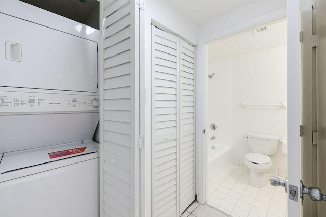 laundry room with light tile patterned flooring, stacked washer and dryer, laundry area, and visible vents