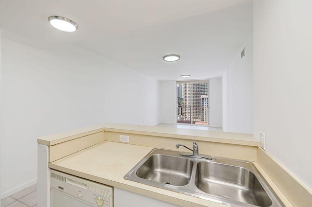 kitchen with a sink, light tile patterned flooring, visible vents, white dishwasher, and light countertops