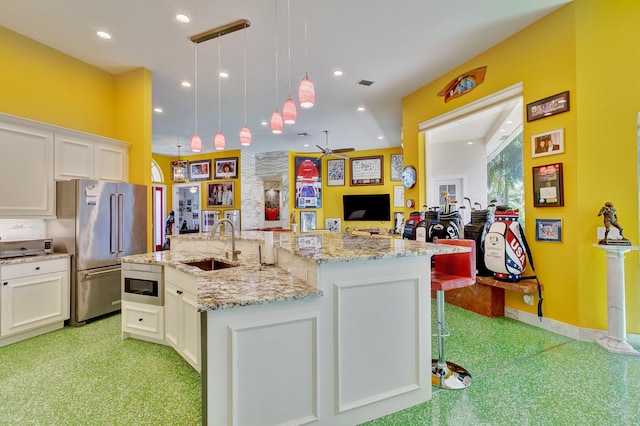 kitchen featuring a kitchen island with sink, a sink, open floor plan, white cabinetry, and high end fridge