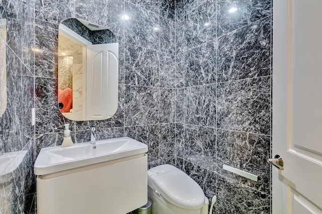 bathroom with tile walls, vanity, and toilet