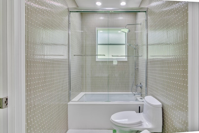 full bath featuring tile walls, toilet, and bath / shower combo with glass door