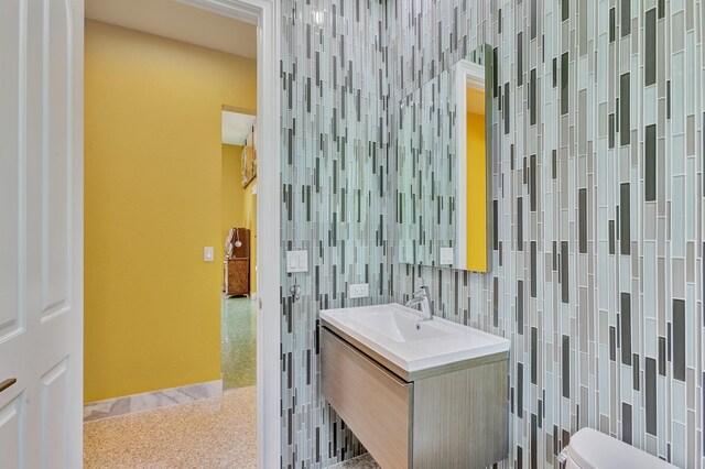 bathroom with toilet, vanity, and tile walls