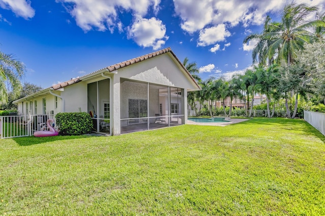 back of house featuring a lawn, a tiled roof, fence private yard, stucco siding, and a sunroom