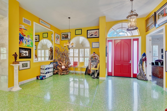 foyer entrance featuring baseboards, a chandelier, and visible vents