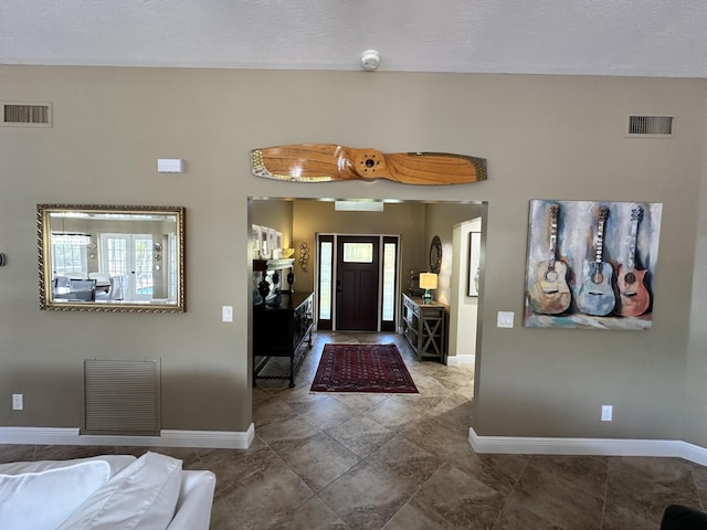 entrance foyer featuring baseboards, a textured ceiling, and visible vents