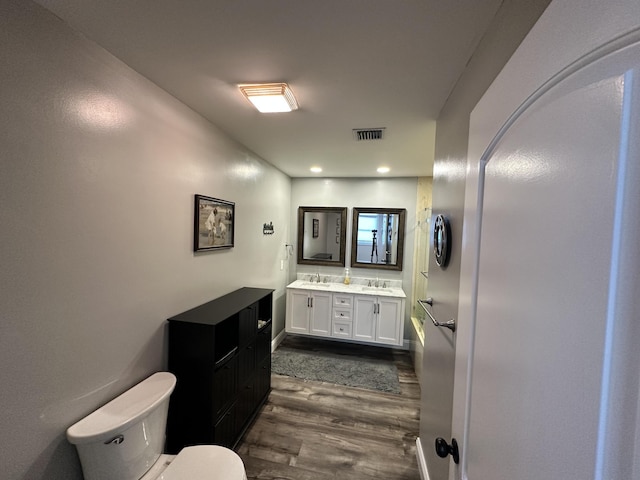 full bath with visible vents, a sink, wood finished floors, and toilet