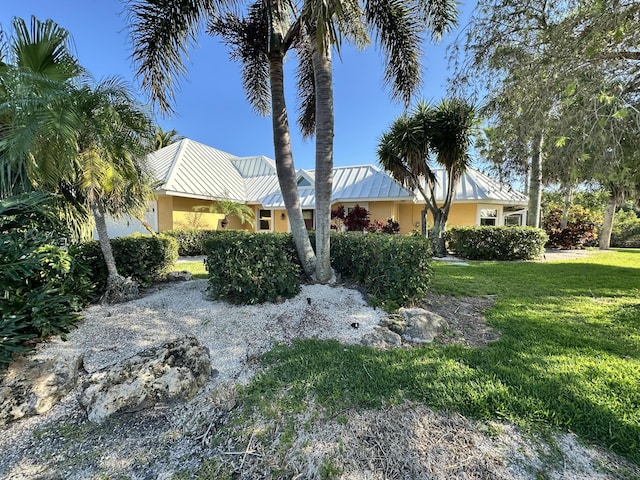 view of front facade featuring a standing seam roof, stucco siding, a front lawn, and metal roof