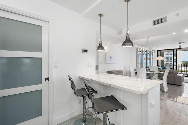 kitchen featuring light stone counters, pendant lighting, a kitchen bar, a peninsula, and visible vents