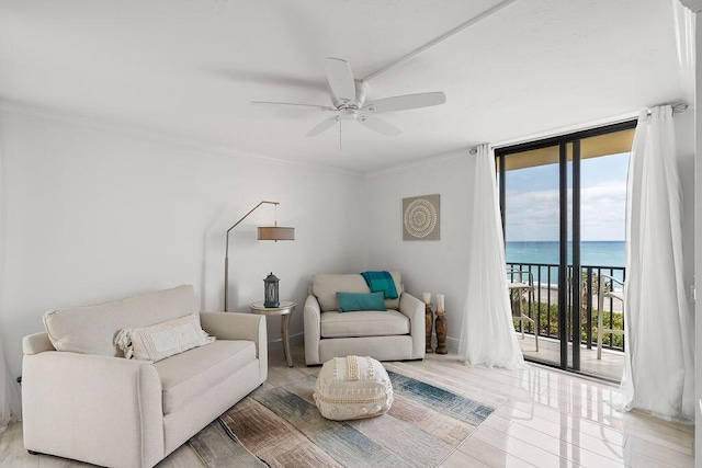 living area featuring floor to ceiling windows, a water view, ceiling fan, and crown molding