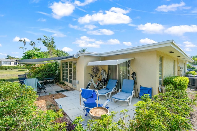 13756 Via Flora Unit A, Delray Beach, FL 33484 - rear view of property with stucco siding, cooling unit, and a patio