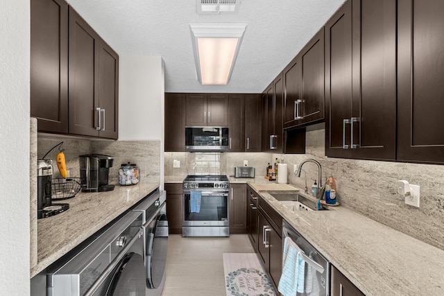 13756 Via Flora Unit A, Delray Beach, FL 33484 - kitchen with light stone counters, dark brown cabinets, a sink, stainless steel appliances, and visible vents