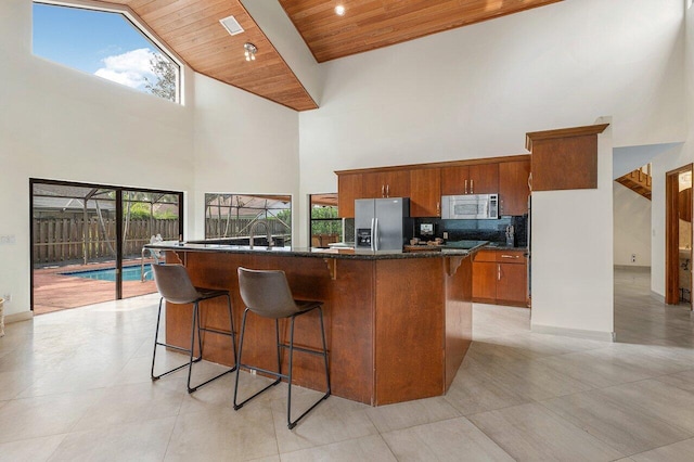 kitchen with a kitchen breakfast bar, high vaulted ceiling, stainless steel fridge, and wood ceiling