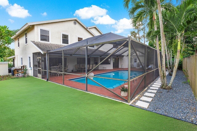 rear view of property featuring fence, an outdoor pool, stucco siding, a patio area, and a lanai