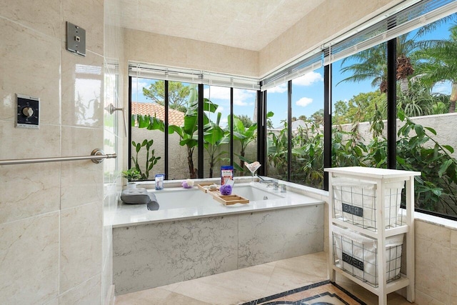 bathroom with tile patterned flooring, a sink, a wealth of natural light, and a garden tub