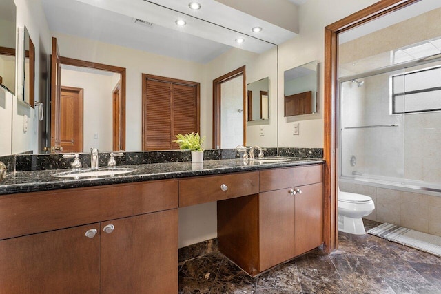 full bathroom featuring double vanity, marble finish floor, toilet, tiled shower / bath, and a sink